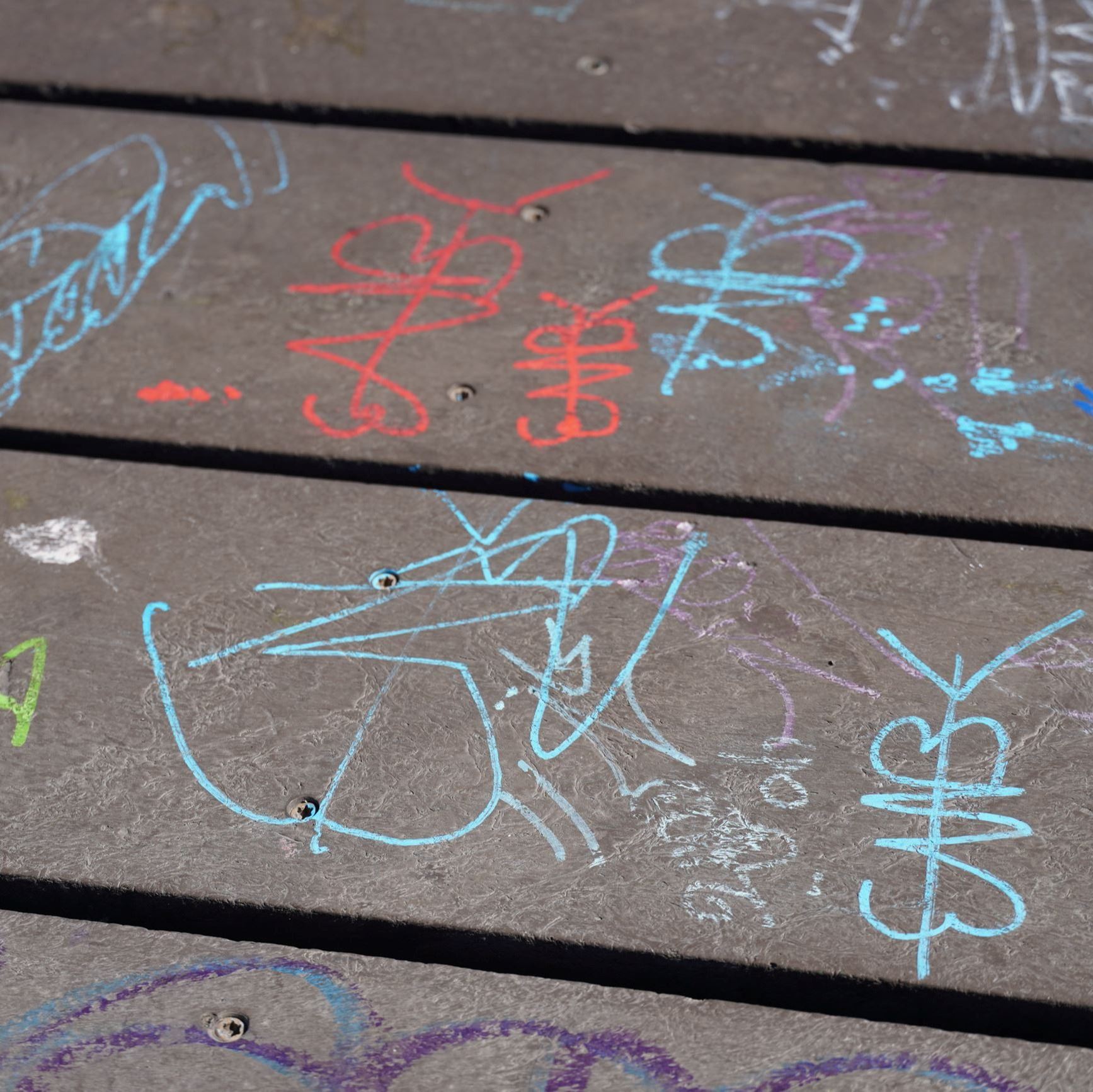 Various graffiti scribbled on sidewalk.