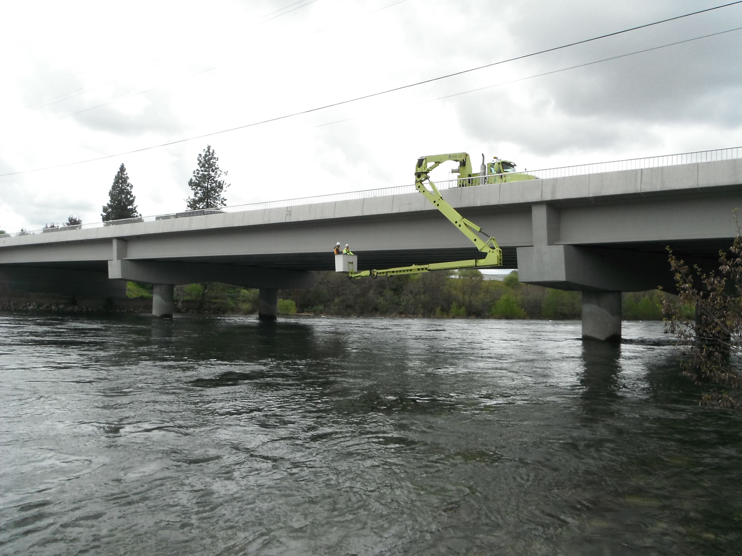 Two engineers inspect the underside of the Sullivan Road bridge.