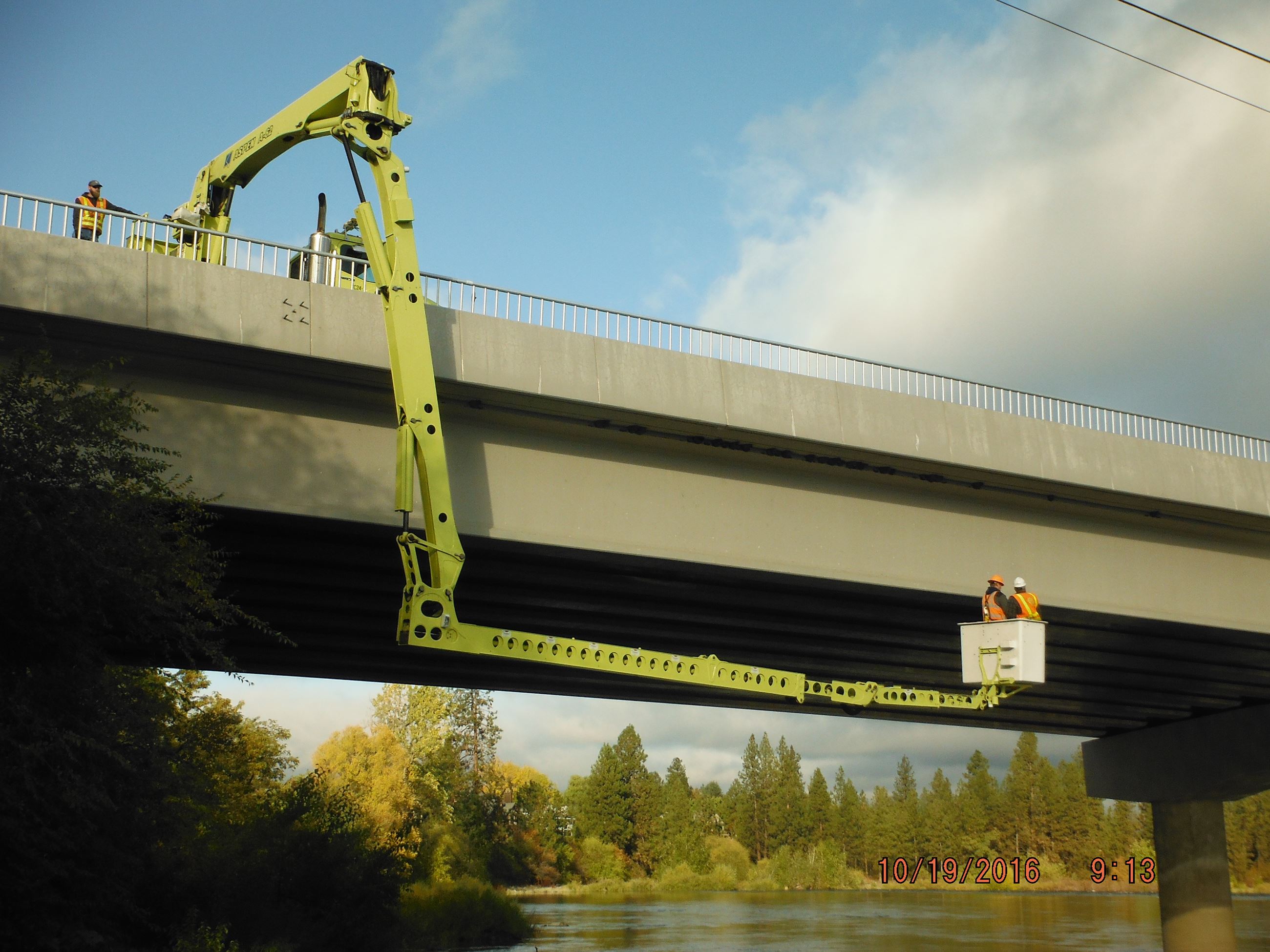 Two engineers inspect the underside of the Sullivan Road bridge.