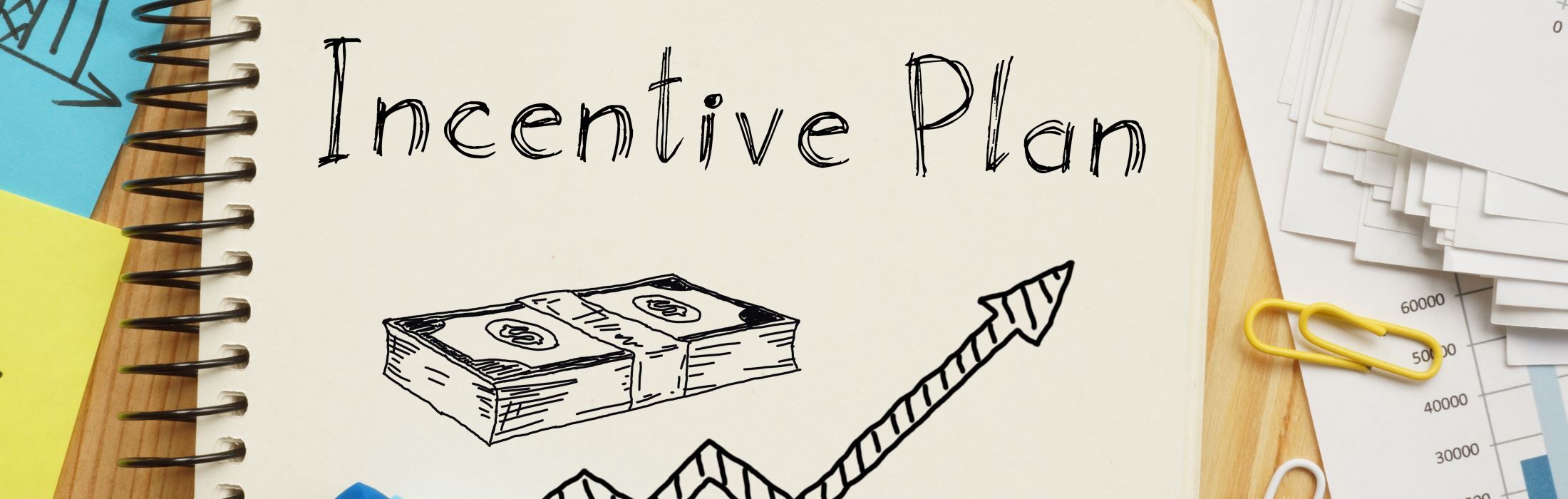 A notebook with a sketch of a stack of dollars and arrows going up that reads "Incentive Plan"